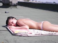 Two gals sunbathing nude at roof